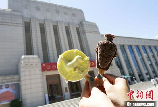 2021年7月30日，游客手拿“銅奔馬”“彩陶瓶”造型的雪糕，在甘肅省博物館前拍照打卡?！「哒?攝