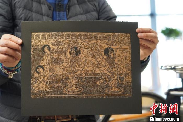 圖為手工書藝人展示敦煌雕版壁畫印刷品。　九美旦增 　攝