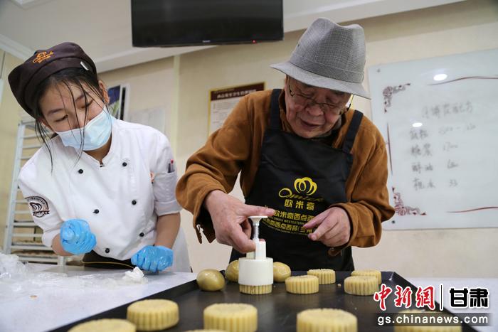 當日，受邀參加活動的臺胞臺屬代表、兩岸婚姻及子女、在甘臺商代表等歡聚一堂。圖為77歲的在甘臺胞潘天鑒制作月餅。九美旦增 攝