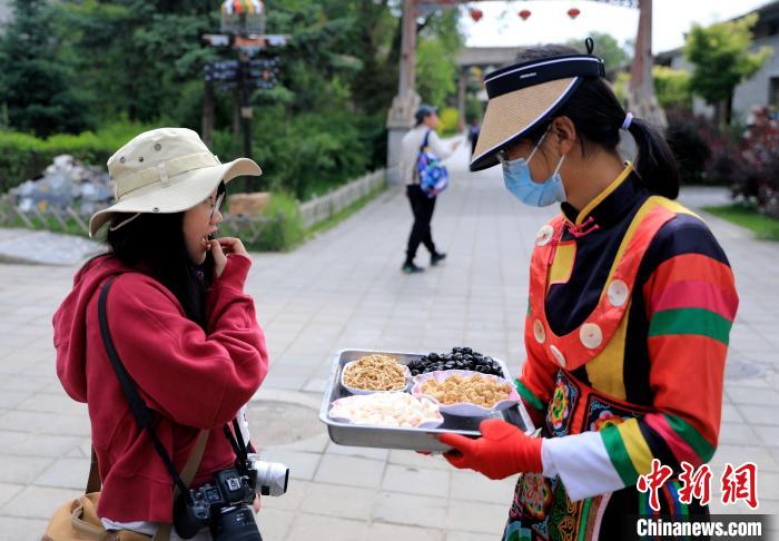 圖為身穿土族服飾的女性介紹當(dāng)?shù)靥厣〕??！⊙Φ?攝