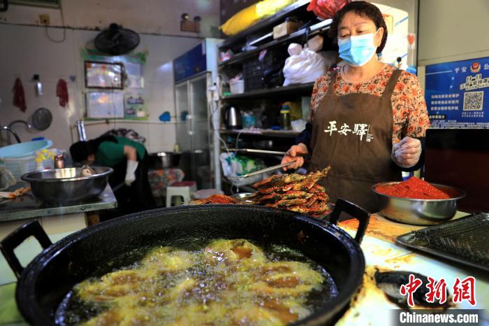 圖為平安驛·河湟民俗文化體驗地內(nèi)的商戶炸干板魚?！⊙Φ?攝