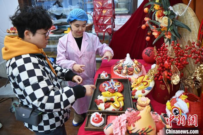 1月25日，隨著春節(jié)臨近，蘭州一花饃店“龍”元素花饃熱銷(xiāo)。圖為工作人員向顧客推薦“龍”元素花饃。九美旦增 攝</p><p>
