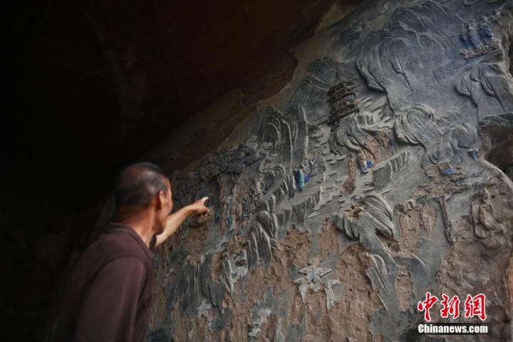 7月15日，甘肅省平?jīng)鍪袥艽h百里石窟長(zhǎng)廊羅漢洞石窟內(nèi)，該窟文保員郭建平介紹窟內(nèi)石刻彩繪壁畫。郭建平家中三代人曾自發(fā)保護(hù)羅漢洞石窟。羅漢洞石窟遺存40余個(gè)窟龕，以北魏至清代風(fēng)格為主。中新社記者 李亞龍 攝