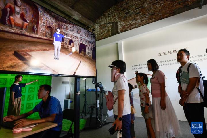7月22日，游客體驗(yàn)“尋境敦煌——數(shù)字敦煌沉浸展”后，在虛擬演播廳拍攝一段真人與洞窟虛擬場(chǎng)景交互的視頻。新華社記者 郎兵兵 攝</p>
<p>